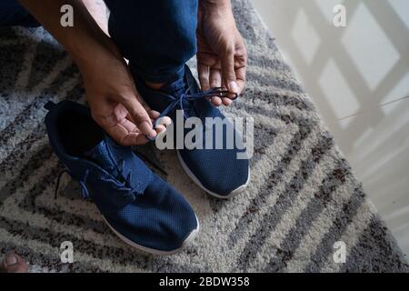 Der Mann trägt Schuhe im Zimmer auf dem Teppich, bevor er ausgeht Stockfoto