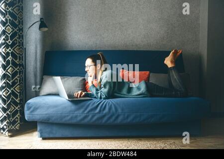 Mädchen, die von zu Hause oder von Studenten, die von zu Hause oder von Freiberuflern lernen, auf einem Laptop arbeiten. Oder sie schaut sich ein Video an oder verwendet das Internet Stockfoto