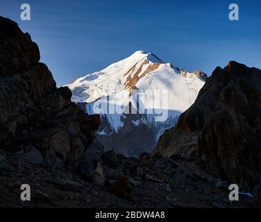 Dankbar schneebedeckten Mount sovetov zwischen Felsen Silhouette bei Sonnenaufgang in Tyan Shan Gebirge in Kasachstan Stockfoto