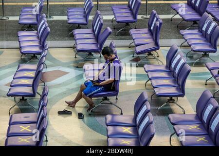 BANGKOK, THAILAND: Ein Mann sitzt allein in einem Wartebereich in Hua Lamphong, Bangkok Railway Station, wo Stühle mit XS markiert wurden, damit Menschen inmitten der COVID-19 Coronavirus Ängste am 6. April 2020 in Thailand soziale Distanz üben können. Stockfoto