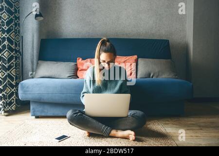 Mädchen, die von zu Hause aus mit einem Laptop arbeiten oder von zu Hause aus studieren oder freiberuflich arbeiten. Sie schaut sich einen Online-Kurs an, macht Hausaufgaben oder surft im Internet. Stockfoto