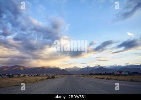 Landschaft der Berge bei Sonnenuntergang und Straße bewölkt Sonnenuntergang Himmel Hintergrund in Kirgisistan Stockfoto