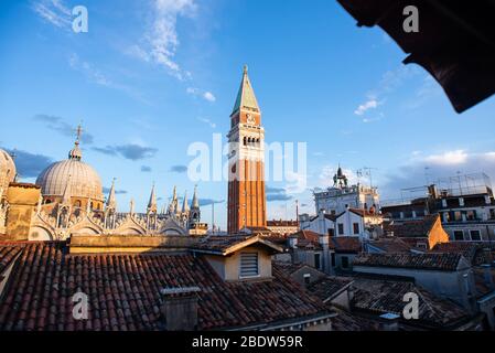 Markusdom und Glockenturm des Markuspitels (Campanile di San Marco) in Venedig, Italien. Sonnenaufgang. Ansicht aus Fenster. Stockfoto