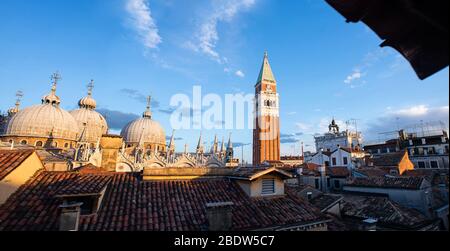 Markusdom und Glockenturm des Markuspitels (Campanile di San Marco) in Venedig, Italien. Sonnenaufgang. Ansicht aus Fenster. Stockfoto