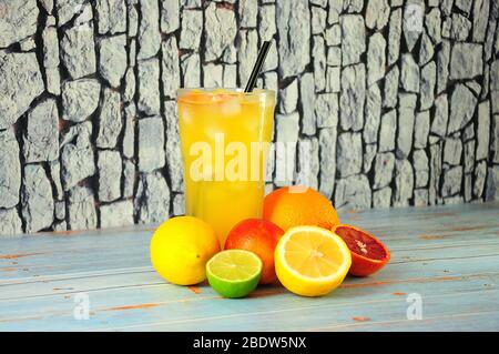 Ein großes Glas Zitrusfrüchte mit Eis und Früchten in der Nähe auf einem Holztisch. Nahaufnahme. Stockfoto