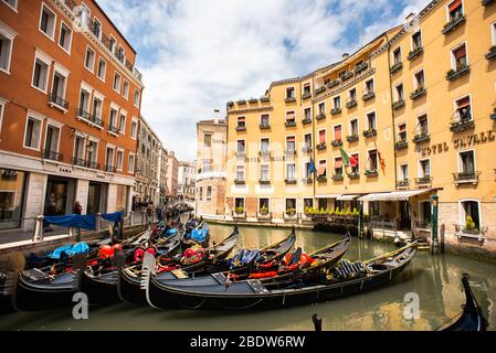 Venedig. Italien - 14. Mai 2019: Vor dem beliebten Cavalletto Hotel verankerte Gondeln. Gruppe von Gondeln in Orseolo Bacino in der Innenstadt von Venedig. Stockfoto