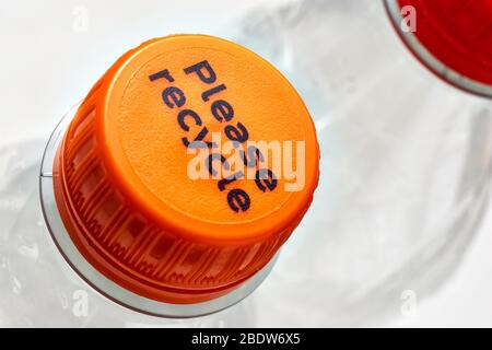 Plastikflaschen und orange und rote Flaschenverschlüsse mit bitte recyceln Nachricht vor weißem Hintergrund. Konzept der Plastikverschmutzung. Stockfoto