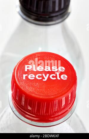 Plastikflaschen und rote und schwarze Flaschenverschlüsse mit Please recycle-Meldung vor weißem Hintergrund. Konzept der Plastikverschmutzung. Vertikales Bild. Stockfoto