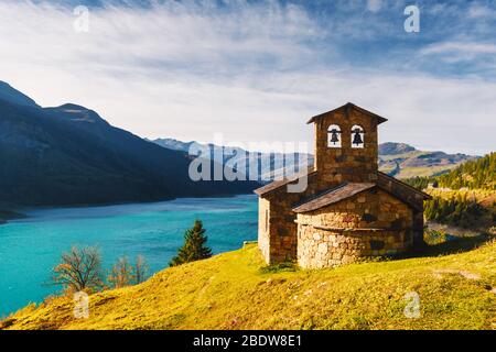 Sonnige malerischen Blick auf Stein Kapelle auf Roselend See (Lac de Roselend) in Frankreich Alpen (Auvergne-Rhone-Alpes). Landschaftsfotografie Stockfoto