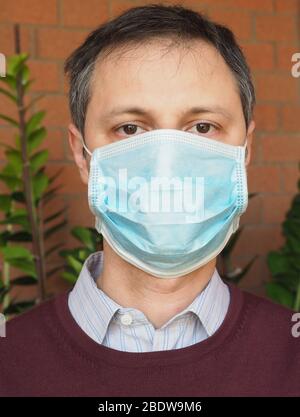 Mann mit chirurgischer Maske verwendet, um die Verbreitung Covid-19 Infektion zu stoppen Stockfoto