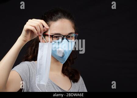 Atemschutzmaske oder Maske das Mädchen hat die Wahl, welche Maske zu tragen ist. Stockfoto