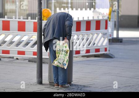 München. April 2020. Öffentliches Leben in Zeiten der Coronavirus-Pandemie am 5. April 2020 in München. Ein alter, armer Mann schaut in einen Mülleimer in der Fußgängerzone und sucht nach Pfandflaschen, Flaschensammlern. Einschränkungen für das Beenden, Kontaktsperre. Kredit: dpa/Alamy Live News Stockfoto