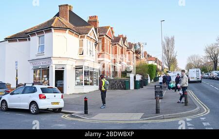 Brighton UK 10. April 2020 - die Käufer stehen am Karfreitagmorgen früh in der Ravens Bakery in Brighton an, wo sie für ihre heißen Brötchen berühmt sind. Die Regierung hat der Öffentlichkeit gesagt, während des Coronavirus COVID-19 Pandemiekrise am Osterwochenende nicht zu gehen. Quelle: Simon Dack / Alamy Live News Stockfoto