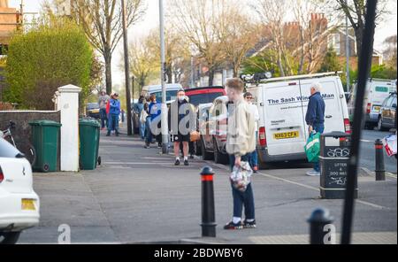 Brighton UK 10. April 2020 - die Käufer stehen am Karfreitagmorgen früh in der Ravens Bakery in Brighton an, wo sie für ihre heißen Brötchen berühmt sind. Die Regierung hat der Öffentlichkeit gesagt, während des Coronavirus COVID-19 Pandemiekrise am Osterwochenende nicht zu gehen. Quelle: Simon Dack / Alamy Live News Stockfoto