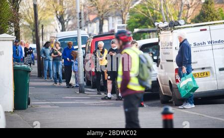 Brighton UK 10. April 2020 - die Käufer stehen am Karfreitagmorgen früh in der Ravens Bakery in Brighton an, wo sie für ihre heißen Brötchen berühmt sind. Die Regierung hat der Öffentlichkeit gesagt, während des Coronavirus COVID-19 Pandemiekrise am Osterwochenende nicht zu gehen. Quelle: Simon Dack / Alamy Live News Stockfoto