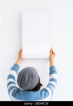 Mädchen hängen weiße Leinwand an der Wand Stockfoto