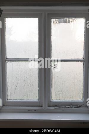 Kondensation auf altem Fensterglas im Winter in England, Großbritannien Stockfoto