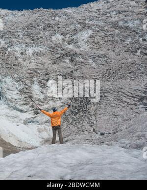 Tourist in orange Windbreaker gekleidet schaut auf Adishi Gletscher ( Lardaad). Der Tropfen dieses Eisfalls ist mehr als 1000 m. Stockfoto