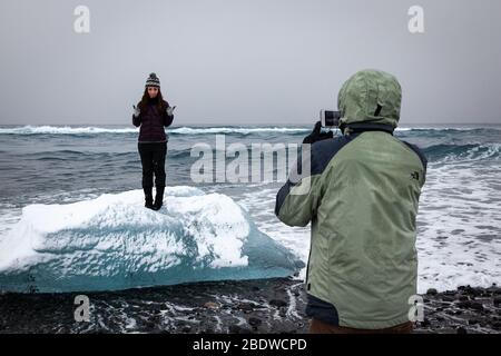 Porträt einer Frau, die auf einem kleinen Eisberg in Island posiert Stockfoto