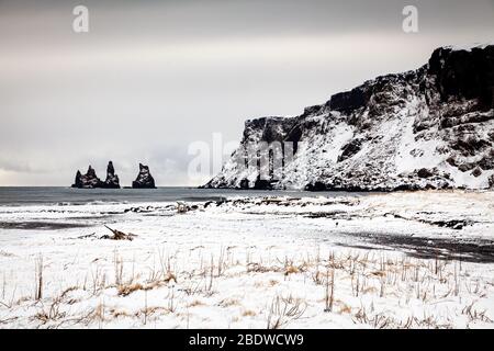 Reynisdrangar Basaltfelsen und Reynisfjall im Winter schneebedeckte Klippen in Vík í Mýrdal an der Südküste Islands Stockfoto