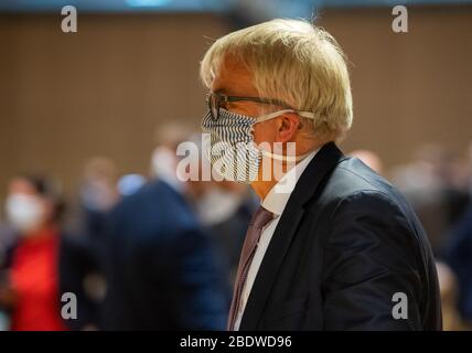09. April 2020, Sachsen, Dresden: Der sächsische Finanzminister Hartmut Vorjohann (CDU) läuft während einer Sondersitzung des Sächsischen Landtags im Internationalen Congress Centrum ICC mit einer Gesichtsmaske durch die Halle. Erstmals seit 1993 wird sich der landtag nicht in seinem offiziellen Plenarsaal treffen. Auf der Tagesordnung stehen unter anderem die Erklärung einer "außerordentlichen Notlage" nach Artikel 95 der Sächsischen Staatsverfassung sowie die Diskussion über die Gesetzesentwürfe der Landesregierung zur Einrichtung eines Sonderfonds "Sächsischer Stabilisierungsfonds" und Stockfoto