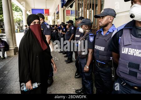 Ein somalischer Flüchtling konfrontiert eine Reihe von Sicherheitskräften, die sie und andere Asylsuchende vom Greenmarket Square in Kapstadt in Südafrika vertreiben Stockfoto