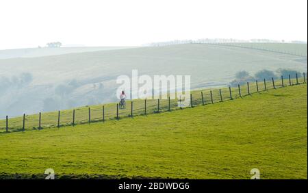 Brighton UK 10. April 2020 - EIN einstrallender Radfahrer in Ditchling Beacon ein bekannter Schönheitsort entlang des South Downs Way in der Nähe von Brighton, wo die Polizei den Parkplatz geschlossen hat. Die Regierung hat der Öffentlichkeit gesagt, nicht über das Osterwochenende zu gehen, trotz der Vorhersage gutes Wetter während der Coronavirus COVID-19 Pandemie-Krise . Quelle: Simon Dack / Alamy Live News Stockfoto