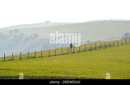 Brighton UK 10. April 2020 - EINZELLÄUFER bei Ditchling Beacon ein bekannter Schönheitsort entlang des South Downs Way in der Nähe von Brighton, wo die Polizei den Parkplatz geschlossen hat. Die Regierung hat der Öffentlichkeit gesagt, nicht über das Osterwochenende zu gehen, trotz der Vorhersage gutes Wetter während der Coronavirus COVID-19 Pandemie-Krise . Quelle: Simon Dack / Alamy Live News Stockfoto