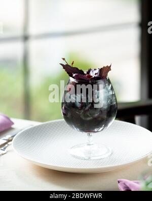 Kalte Beeren mit Basilikum auf dem Tisch Stockfoto