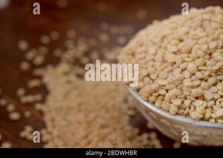 Split White Urad Dal. Vigna mungo Bohnen in einer Silberschale auf einem hölzernen alten Tisch. Rustikaler Stil Stockfoto