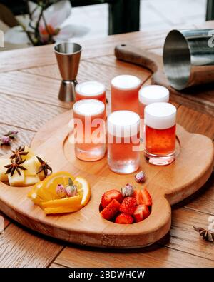 Gläser Bier mit Schaum und in Scheiben geschnittenen Früchten auf dem Brett Stockfoto