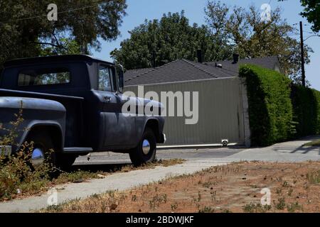 Alte rostige schwarze LKW, auf der Straße vor einem weißen Haus geparkt. Stockfoto