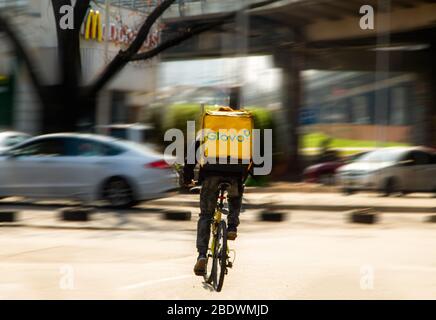 Der Glovo Courier auf dem Fahrrad, der zum Fast-Food-Restaurant McDonalds fährt, um eine Bestellung abzuholen und zu liefern. Bewegung. Ausbruch des Coronavirus, Kiew, Ukraine - 08. April 2020 Stockfoto
