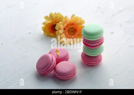 Eine französische süße Delikatesse, bunte Makronen Varietät Nahaufnahme mit Blumen auf weißem Hintergrund. Leckere Makronen bunte Textur. Stockfoto