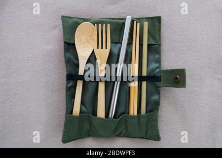 Wiederverwendbare und umweltfreundliche Utensilien umfassen Bambuslöffel, Gabel, Essstäbchen, kleines Stroh, ein großes Edelstahl-Stroh in einem gefalteten Stoffbeutel. Stockfoto