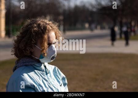 Mädchen mit Gesicht Schutzmaske im Freien. Kopieren Sie den Bereich auf verschwommenem Hintergrund. Konzept der Gesundheitsproblem. Schutz vor Viren und Krankheiten Stockfoto