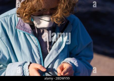 Nahaufnahme von Mädchen mit ihrem Handy. Junge Frau trägt eine medizinische Maske, um die Atemwege vor Viren und Krankheiten zu schützen. Das Konzept von Stockfoto
