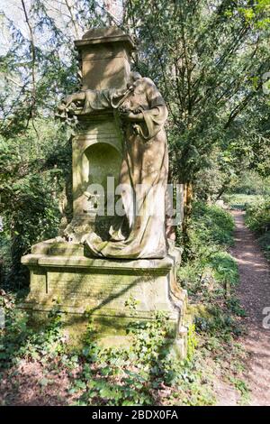 Eine zerstörte und kopflose Steinfigur einer jungen Frau, die einen Grabstein auf einem alten stillisierten Friedhof in England schmückt Stockfoto