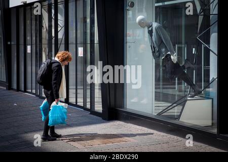 Frau und Schaufensterpuppe scheinen gemeinsam eine Inschrift in einer Grundplatte in der Schildergasse, Köln, zu lesen. Frau und Schaufensterpup Stockfoto