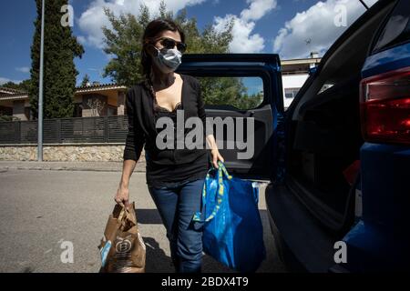 Frau, die während der Sperrung von Covid19 in Katalonien, Spanien, Einkäufe vom Auto nach dem Weg zum Supermarkt trägt Stockfoto