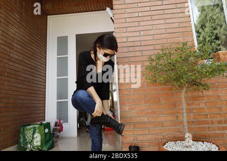 Frau, die Schuhe auszieht, bevor sie während der Sperrung von Covid19 in Katalonien, Spanien, ins Haus geht Stockfoto