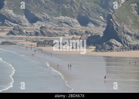 Die Menschen laufen am Tolcarne-Strand in Newquay an der Nordküste von Cornwall, während Großbritannien weiterhin in der Sperre bleibt, um die Ausbreitung des Coronavirus einzudämmen. Stockfoto