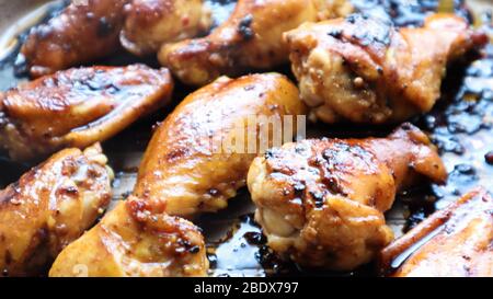 Gebratene Hähnchenflügel mit Kruste in einer Pfanne Nahaufnahme. Gebackenes Huhn in Teriyaki-Sauce auf einem Backblech im Ofen, selektiver Fokus Stockfoto