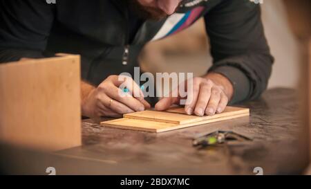 Zimmerei arbeiten - bärtiger Mann macht Markierungen auf dem Holz. Mittelaufnahme Stockfoto