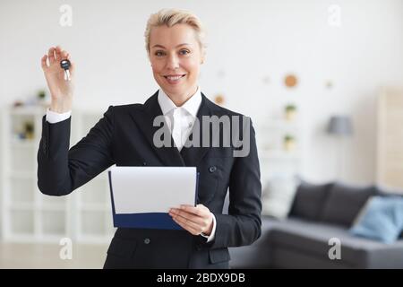 Porträt der reifen Frau arbeitet als Immobilienmakler mit Schlüsseln von zu Hause in der Hand und lächelt vor der Kamera Stockfoto