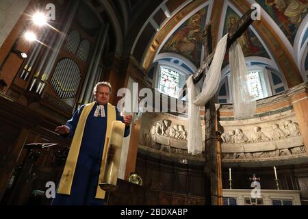 Am 0001. April 11 verhängt, zündet der Pfarrer Peter Sutton die Osterkerze an, während er die Ostersonntagspredigt im Hauptheiligtum der Pfarrkirche St. Cuthbert in Edinburgh aufzeichnet, Die Kirche hat Predigten gestreamt, während Großbritannien weiterhin in der Sperre bleibt, um die Ausbreitung des Coronavirus einzudämmen. Stockfoto