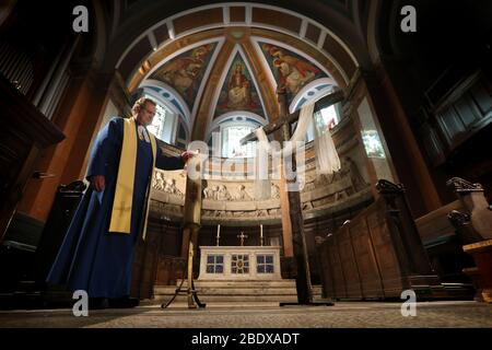 Der Pfarrer Peter Sutton zündet die Osterkerze an als er die Ostersonntagspredigt im Main Sanctuary der Pfarrkirche St. Cuthbert in Edinburgh aufzeichnet, hat die Kirche Predigten gestreamt, während Großbritannien weiterhin in der Lockdown-Funktion ist, um die Ausbreitung des Coronavirus einzudämmen. Stockfoto