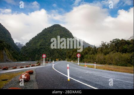 Straße durch Franz Josef National Park, Neuseeland. Berglandschaft, blau, bewölkter Himmel Hintergrund Stockfoto