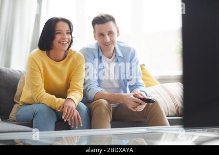 Junges Paar zu Hause entspannen sie sitzen auf dem Sofa und schauen ein Interessantes Programm im Fernsehen Stockfoto