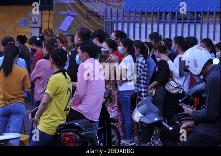 Keine soziale Distanz, Chaos, da kambodschanische Bekleidungsfabrikarbeiter, die meisten tragen Gesichtsmasken, sich an einer Bank anstellen am 1. Tag Phnom Penh alle Straßen in und aus der Stadt vor kambodschanischem Neujahr und während der Coronavirus-Pandemie absperrt. Phnom Penh, Kambodscha. April 2020. © Kraig Lieb Stockfoto